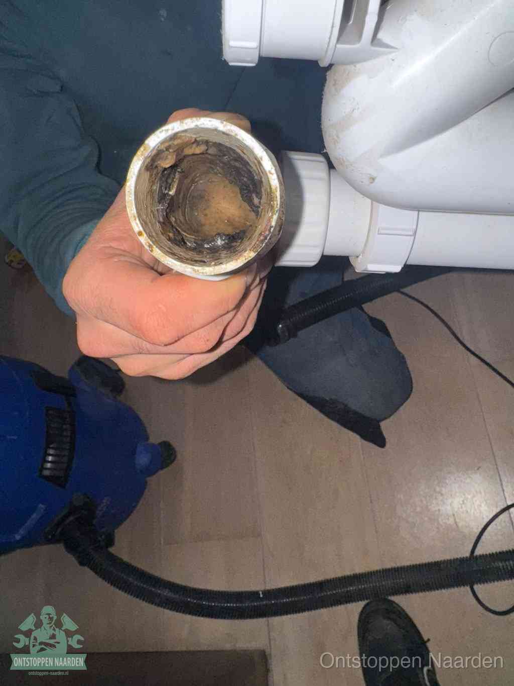 Een losgekoppeld PVC-afvoerbuisstuk dat van binnen volledig is dichtgeslibd met vet en vuil, de meest voorkomende oorzaak van verstoppingen in Naarden