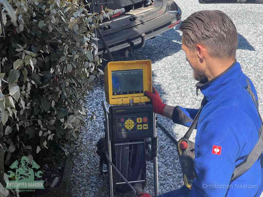 Een monteur bedient een rioolinspectiecamera met monitor en haspel om de verstopping in beeld te brengen in Naarden