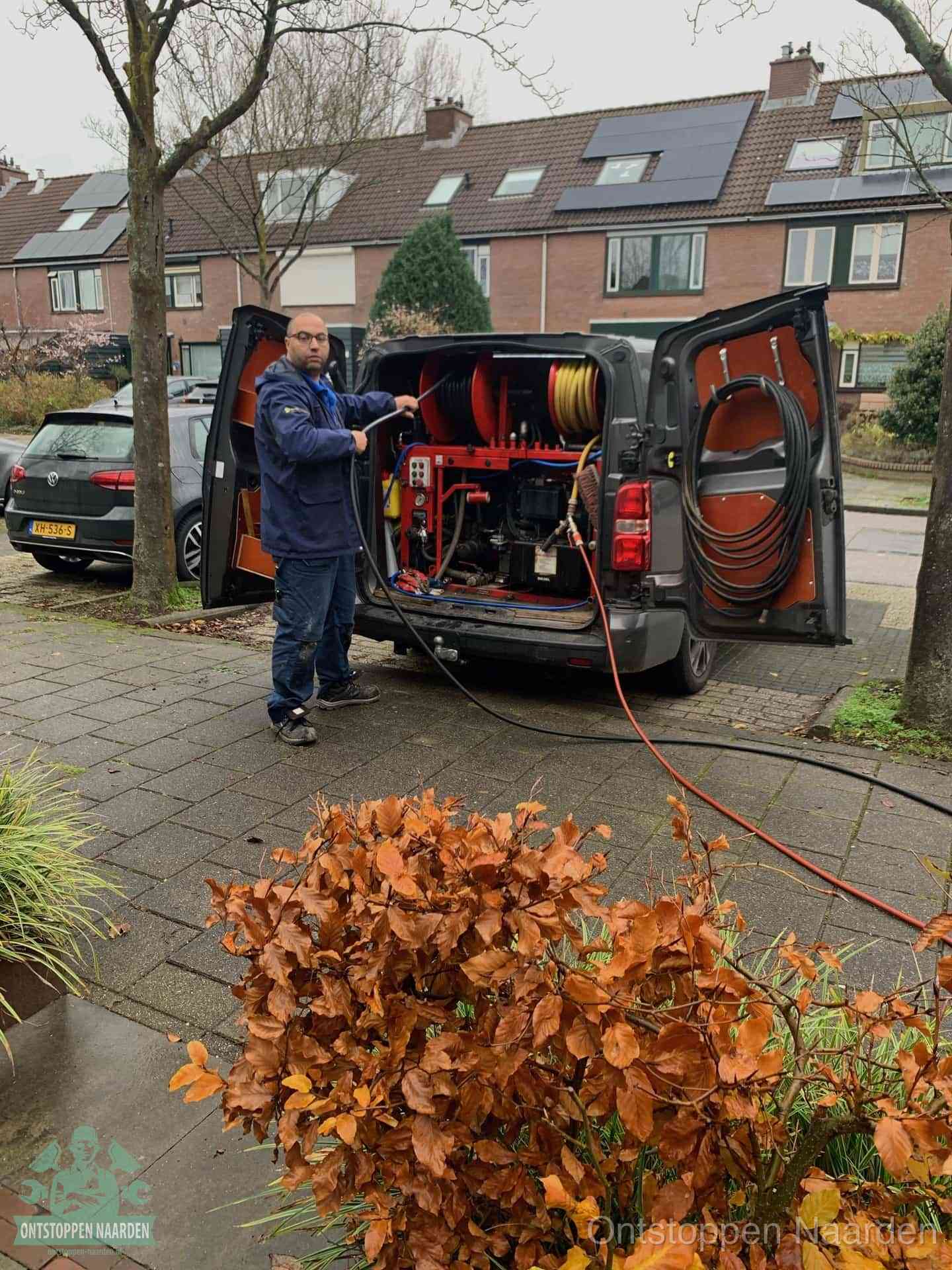 Een monteur staat bij zijn open bestelbus met hogedruk-rioolreinigingsapparatuur, klaar om binnen 30 minuten uit te rukken voor een spoedverstopping in Naarden