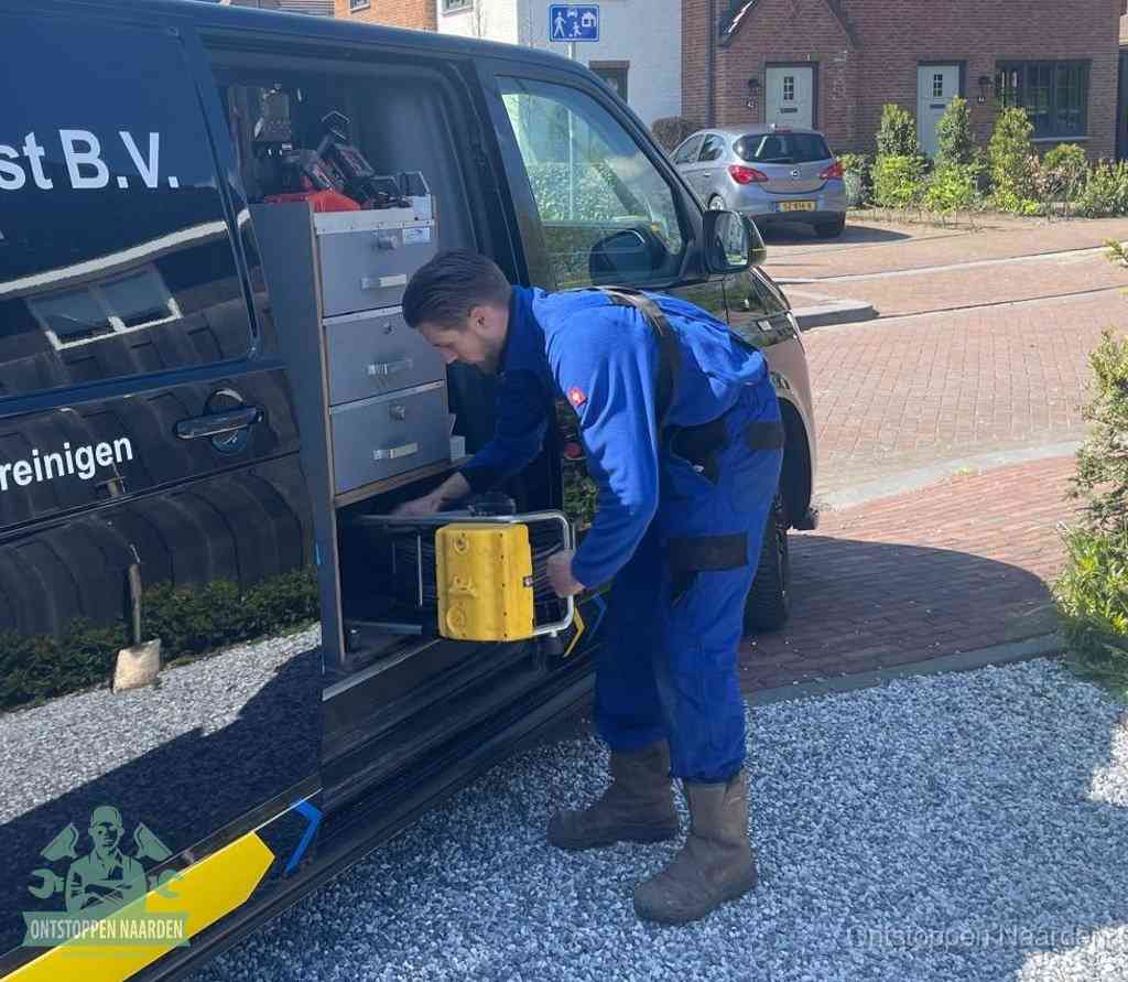 Een monteur pakt gereedschap uit de bedrijfsbus, het moment om een professionele ontstoppingsdienst in te schakelen in Naarden