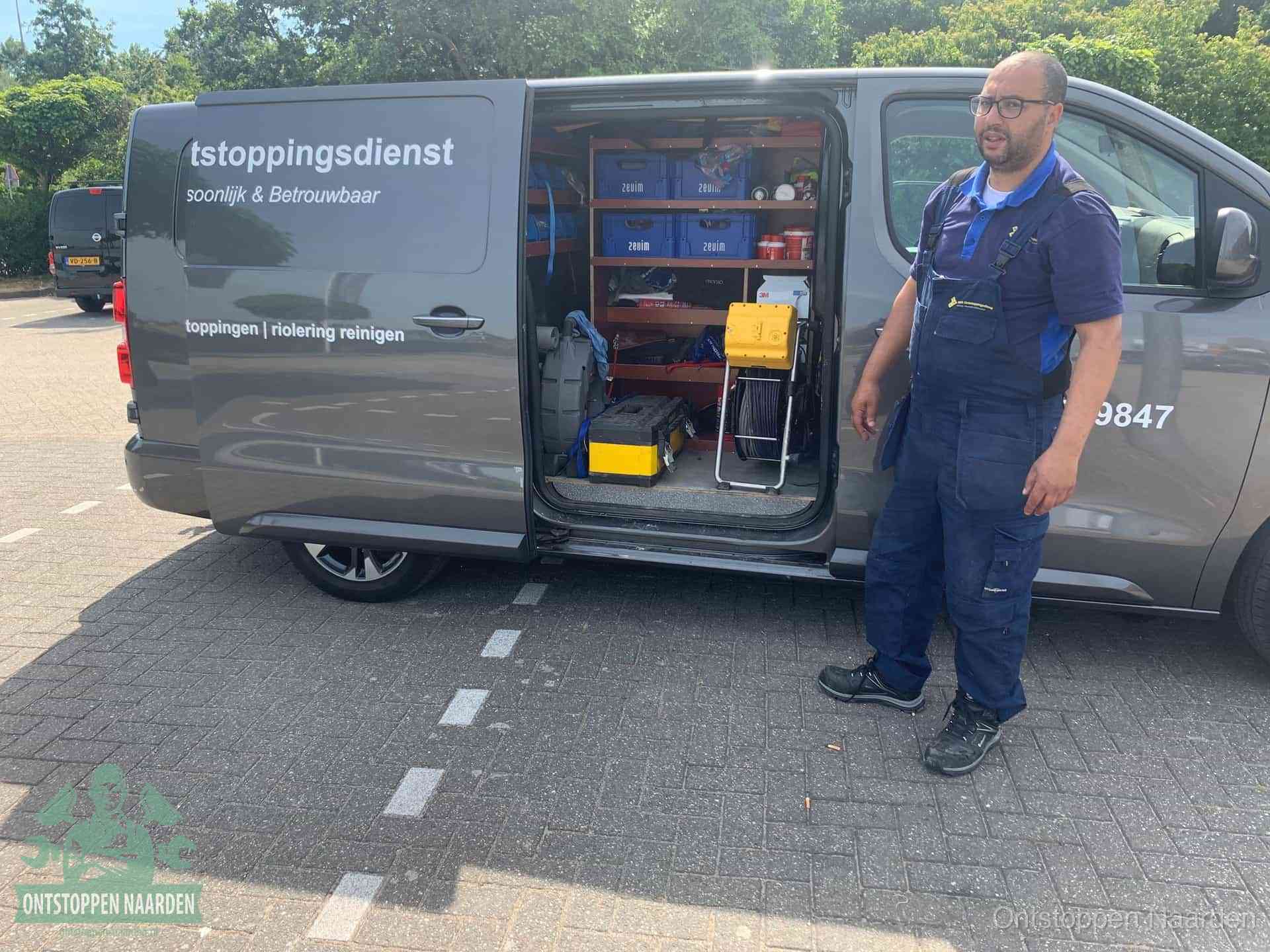 Een monteur staat klaar bij zijn bedrijfsbus met gereedschap, de vaste werkwijze van de ontstoppingsdienst in Naarden
